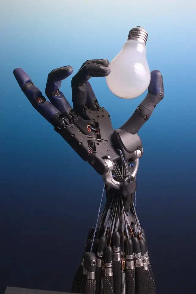 An articulated robotic hand holding a light bulb
