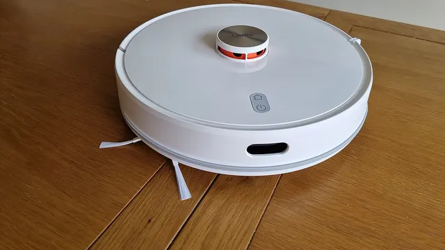 A robot vacuum and mop with a LiDAR sensor, sitting in front of its automatic emptying station