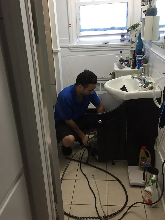 A technician unclogging a sink